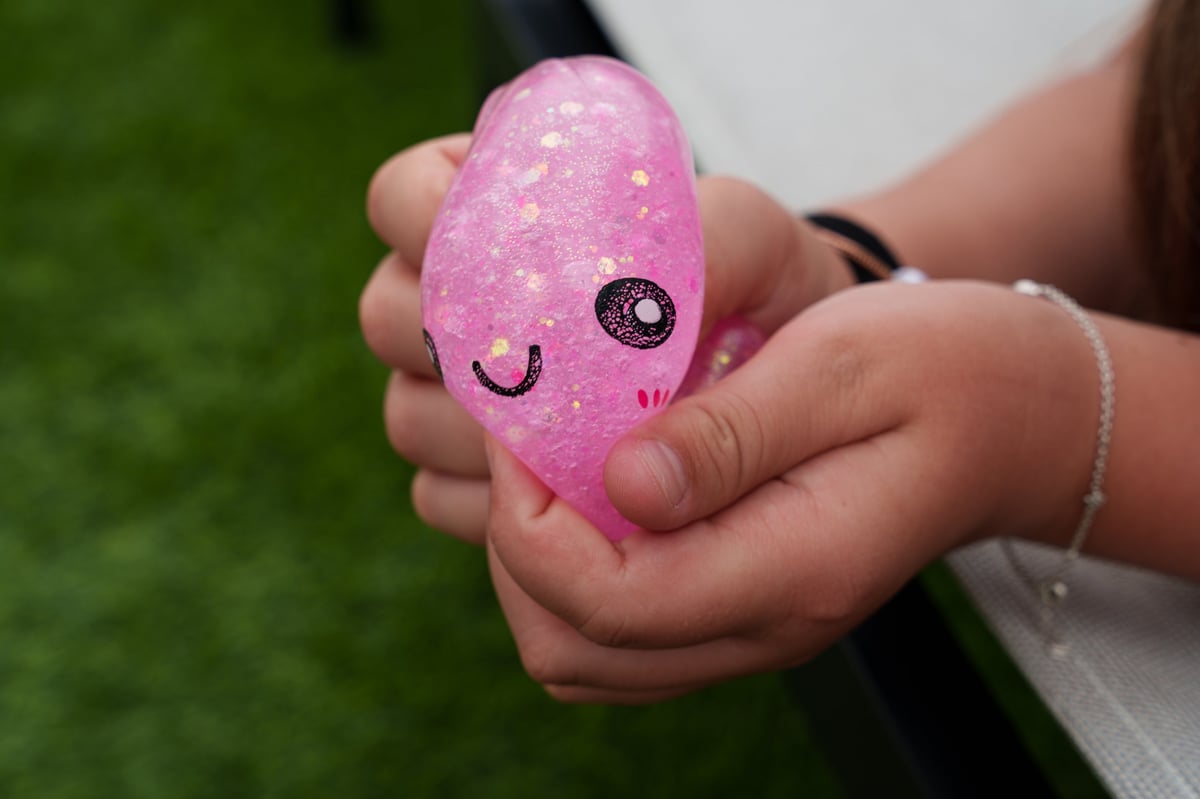 A child's hand squeezing a pink glitter squishy dumpling toy in close-up